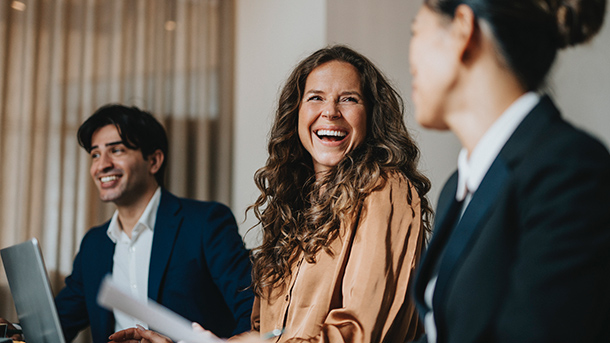 Happy businesswoman sitting among colleagues laughing